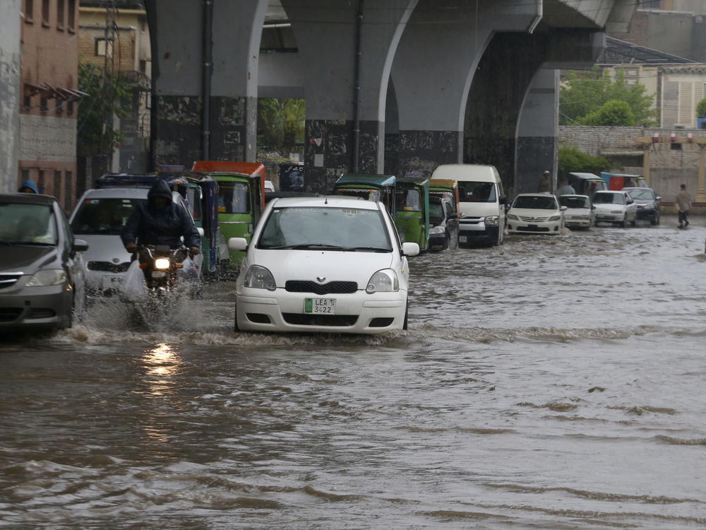 A motorcyclist and car drivers drive through a flooded road caused by heavy rain in Peshawar, Pakistan, Monday, April 15, 2024.