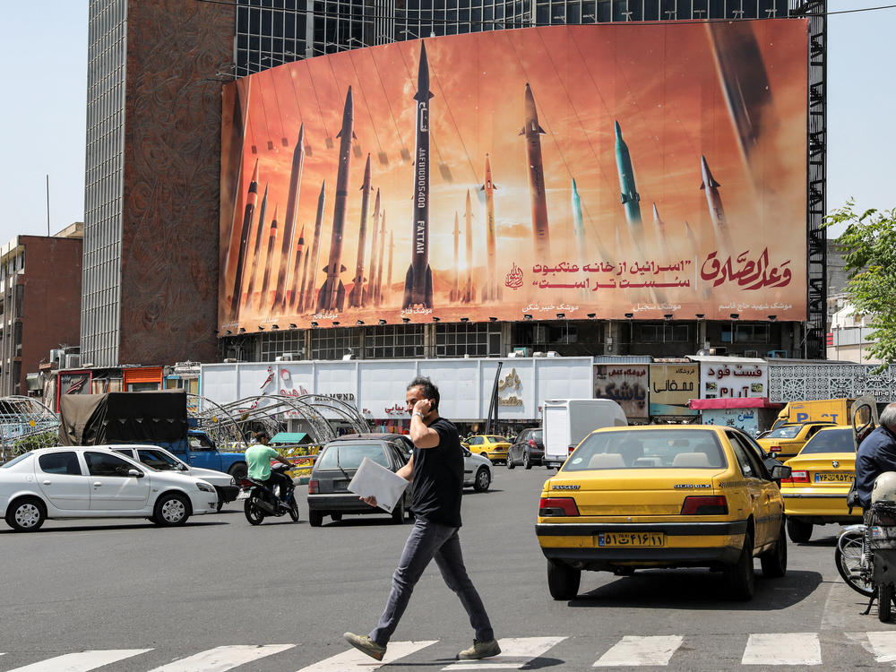 A billboard in central Tehran, Iran, depicts named Iranian ballistic missiles in service, with text in Arabic reading 