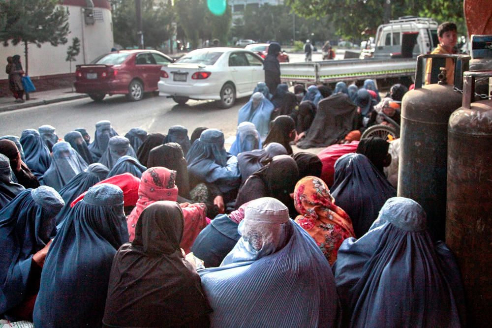 Women in burkas sit outside a bakery in Kabul in this photo from 2022. Impoverished women from hilltop slums around Kabul were flocking to bakeries in the city, silently waiting to see if someone will purchase bread for them.