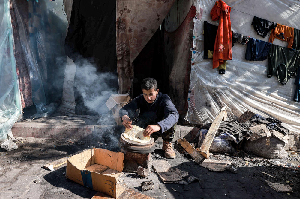 A boy prepares bread to eat outside a tent sheltering displaced Palestinians in Rafah in the southern Gaza Strip on February 8.