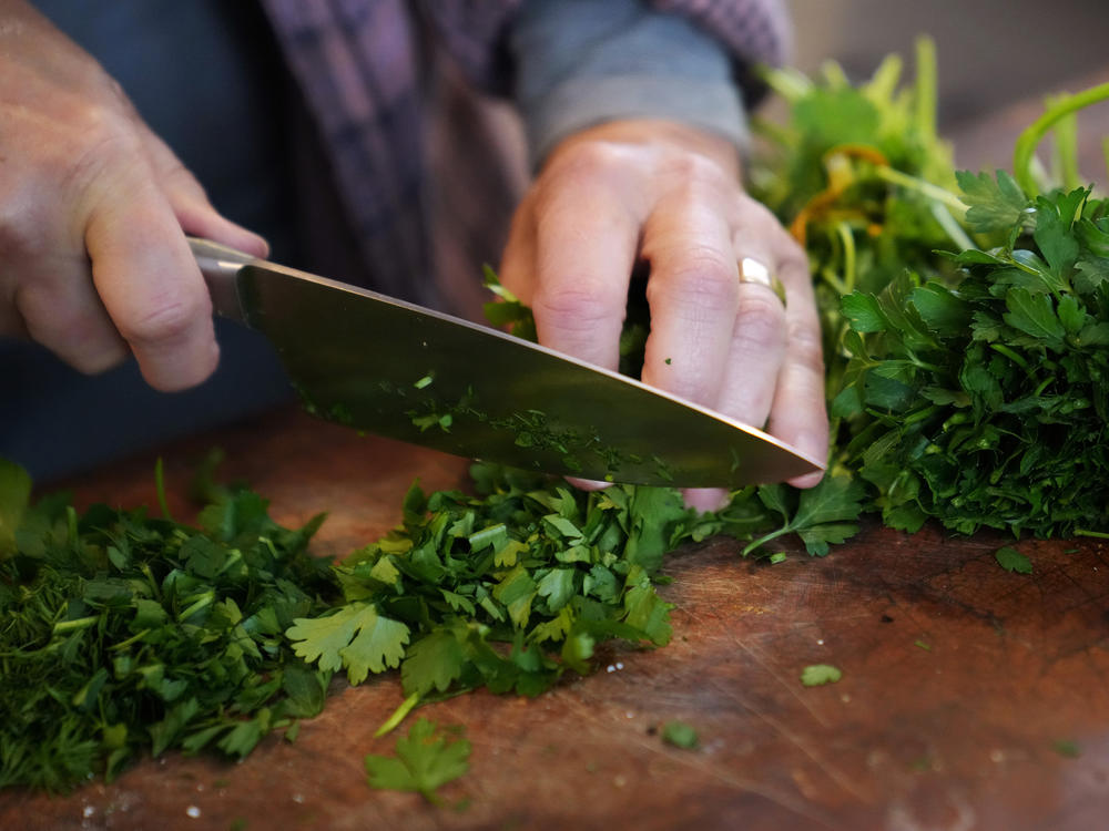 Joan Nathan chops up fresh herbs for her soup and rolls matzo balls in her kitchen in Washington, D.C.