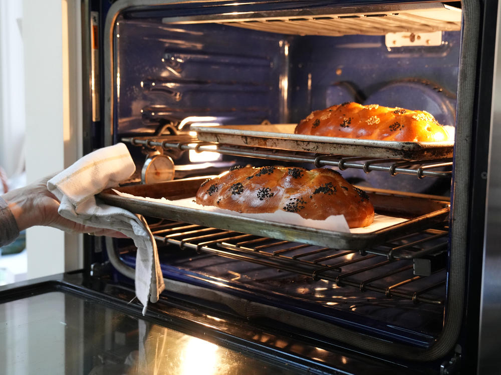 Nathan pulls two loaves of challah out of the oven at her home in Washington, D.C.