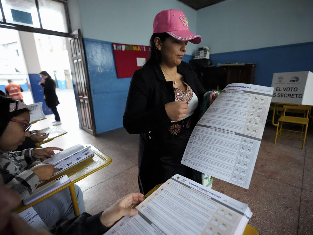 A woman holds the ballot to vote in a referendum proposed by President Daniel Noboa to endorse new security measures aimed at cracking down on criminal gangs fueling escalating violence, in Quito, Ecuador, Sunday, April 21, 2024.