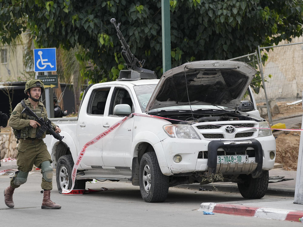 Israeli soldier walks by a pickup truck used by Palestinian militants in Sderot, Israel, on Saturday, Oct. 7, 2023.