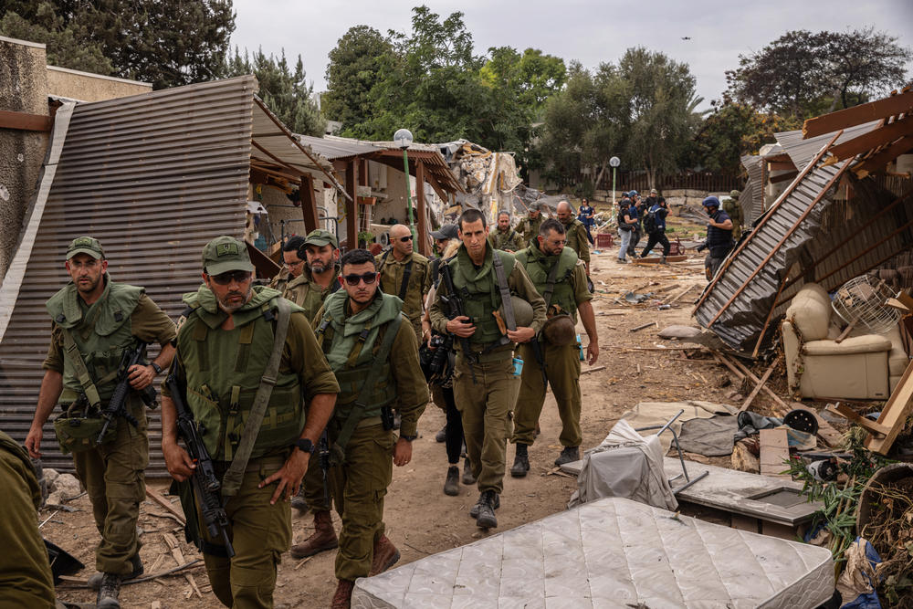 Israeli soldiers survey the destruction in Kfar Aza, Israel, on Oct. 27, 2023. The small kibbutz community near the Gaza border was raided by Hamas militants during the Oct. 7 attacks. They killed over 60 people, abducted at least 18 and destroyed scores of homes.