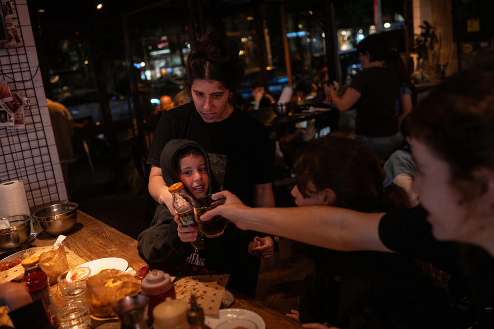 Hadar Tiv, 5, his mother Elan, 33, and their family members raise a glass to his grandfather Keith Siegel during dinner at a restaurant in Tel Aviv, March 28.
