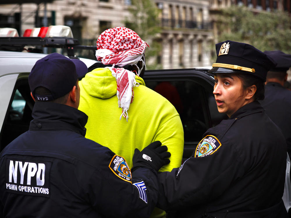 NYPD officers detain a person as pro-Palestinian protesters gather outside of Columbia University on Thursday.
