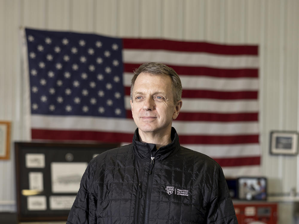 Dr. Todd Rasmussen stands in his home office in Rochester, Minn. He is a former combat surgeon who did six tours in Iraq and Afghanistan.