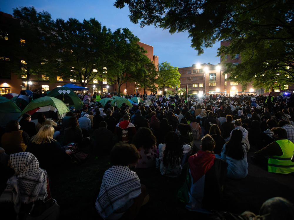 Thousands of people sit silently while fellow demonstrators pray during a rally at George Washington University on Thursday night.