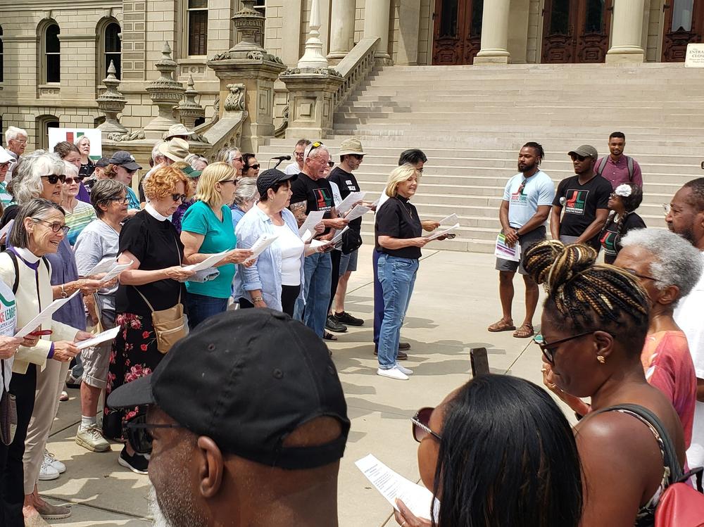 In June of 2023, the Justice League of Greater Lansing organized an event in front of the Michigan State Capitol for Juneteenth where white congregants of faith communities and other allies read a public apology issued by Presbyterian Church USA to descendants of enslaved African Americans.