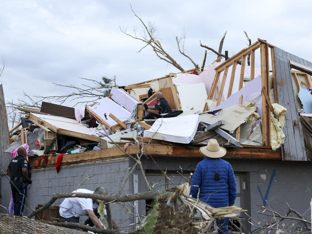Omaha police officers search a home for a family after a tornado leveled dozens of homes near the city on Friday.