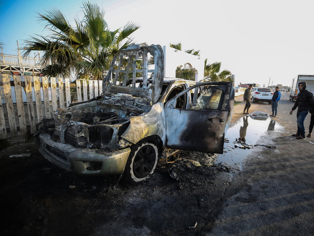People stand next to a vehicle in Deir Al-Balah, in the central Gaza Strip, on April 2, where workers from the World Central Kitchen (WCK), were killed in Israeli airstrikes, according to the NGO.