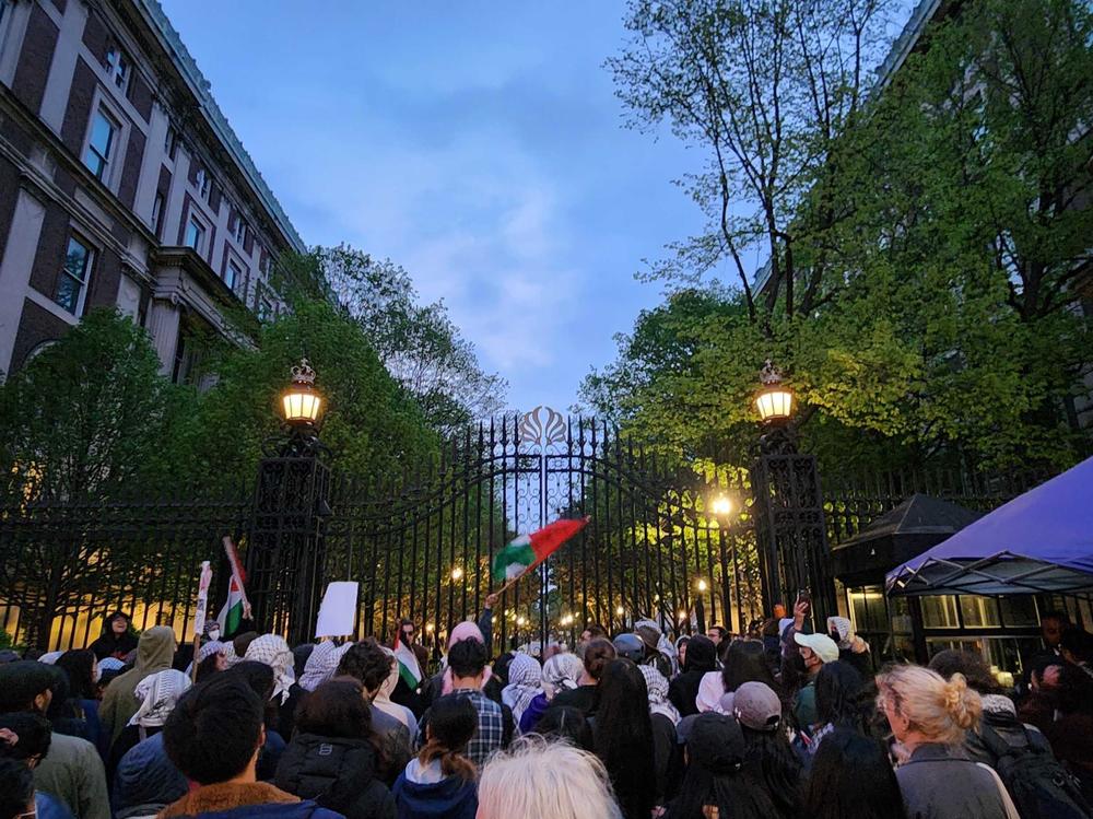 A crowd gathers Tuesday evening by the gates in front of Columbia University's Hamilton Hall.