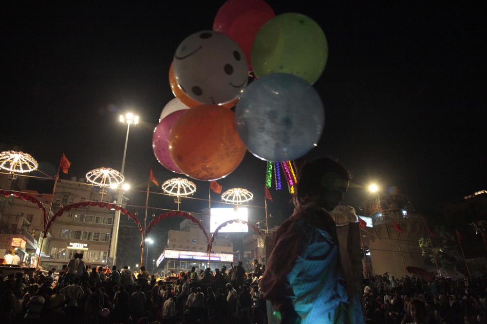 A child selling balloons amid worshippers and tourists sitting on boats facing the bank of the Ganges River in the holy Hindu city of Varanasi to watch the Ganga Aarti, a ritual of devotion to the venerated river.