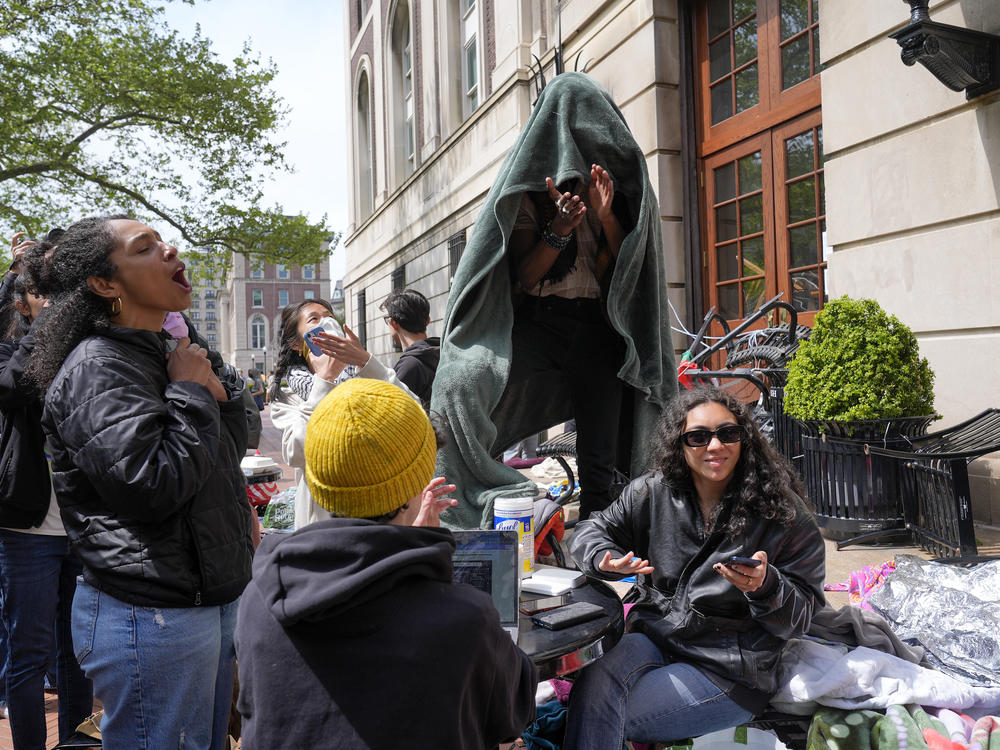 Student protesters react to the news that Brown University has agreed to hear a divestment proposal as they camp near the entrance to Hamilton Hall on the campus of Columbia University, Tuesday, in New York.