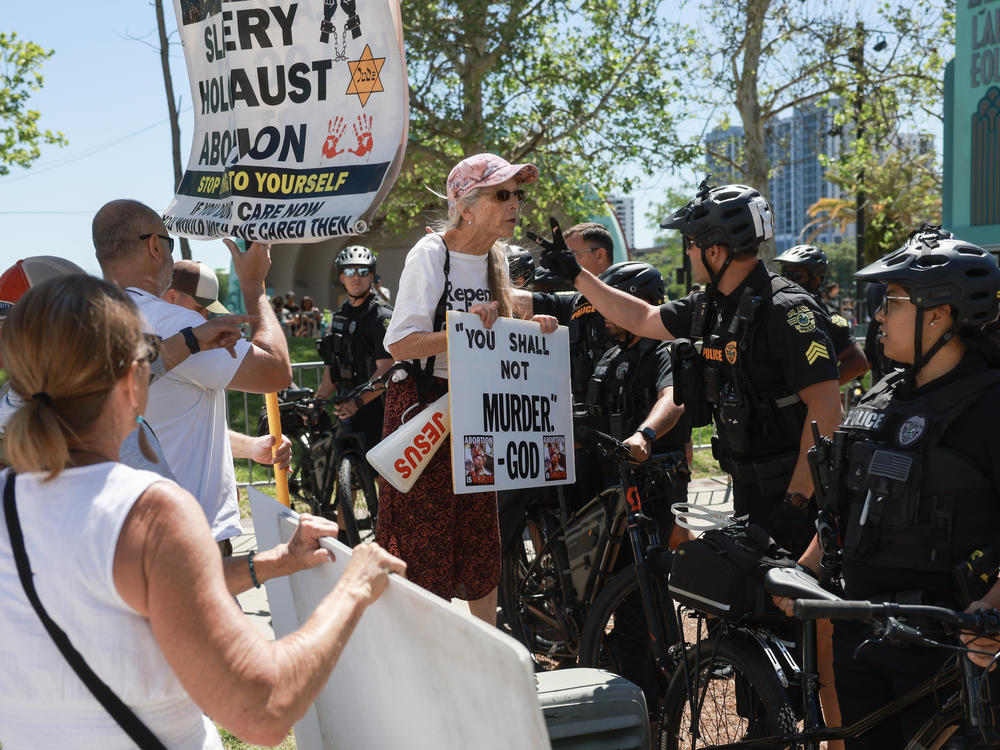Orlando Police officers move back anti-abortion rights protesters near the 