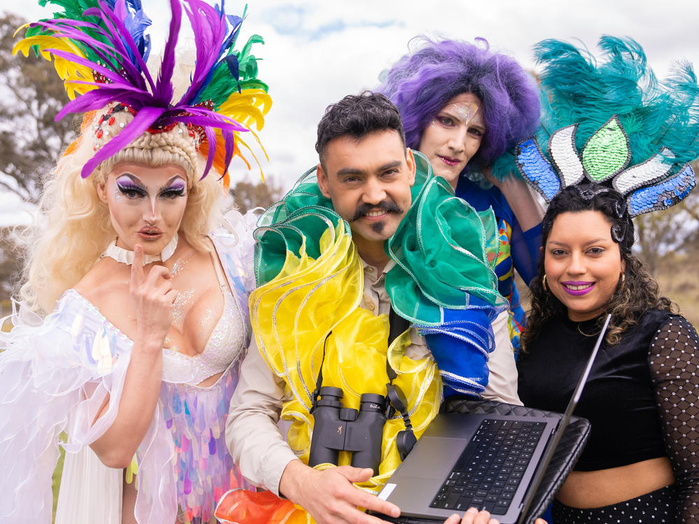 Weliton Menário Costa (center) holds a laptop while surrounded by dancers for his music video, 