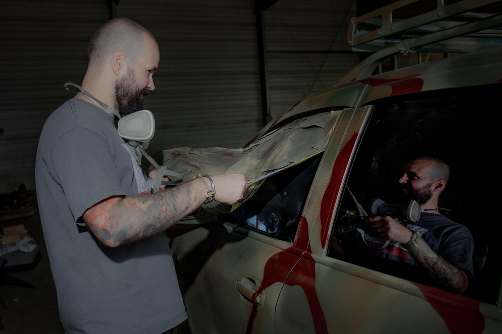 Neak removes the covering from the windows of a freshly painted truck.