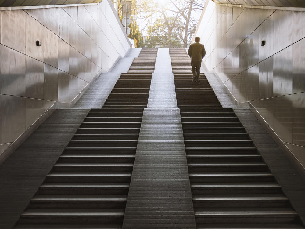 A man is walking up the steps of an underground passage
