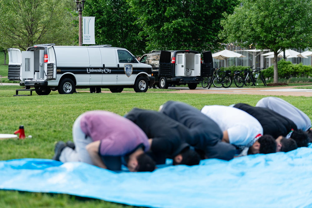 Prisoner vans are readied as Muslims pray during a pro-Palestine rally on April 27 at Washington University.