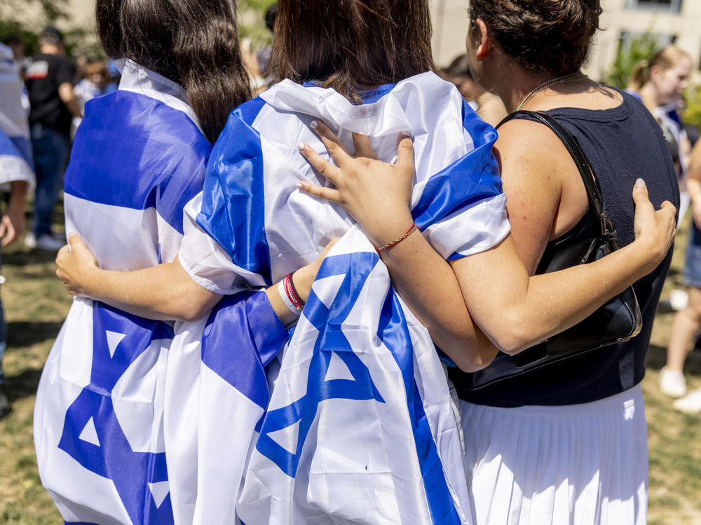 Pro-Israel counterprotesters draped in Israeli flags embrace at George Washington University.