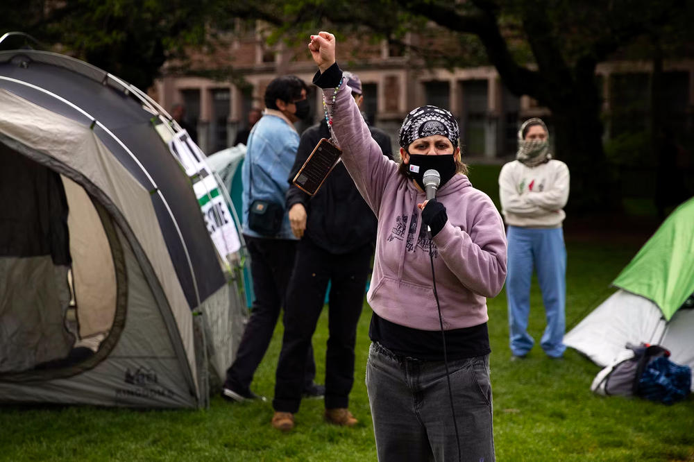 University of Washington alumni Gemini Gnull, with Freedom Road Socialist Organization, leads a chant as students set up what they are calling the UW Palestine Encampment on April 29, on the University of Washington campus in Seattle.