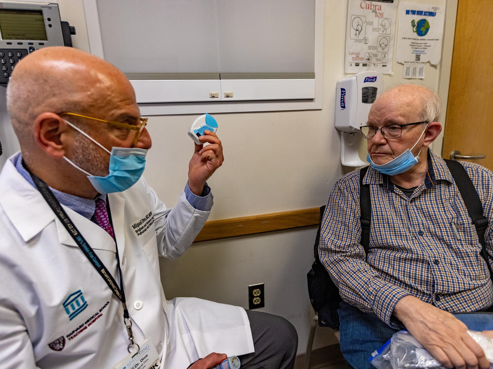Miguel Divo shows his patient, Joel Rubinstein, a dry powder inhaler. It's an alternative to some puff inhalers that emit potent greenhouse gases, but is equally effective for many patients with asthma.