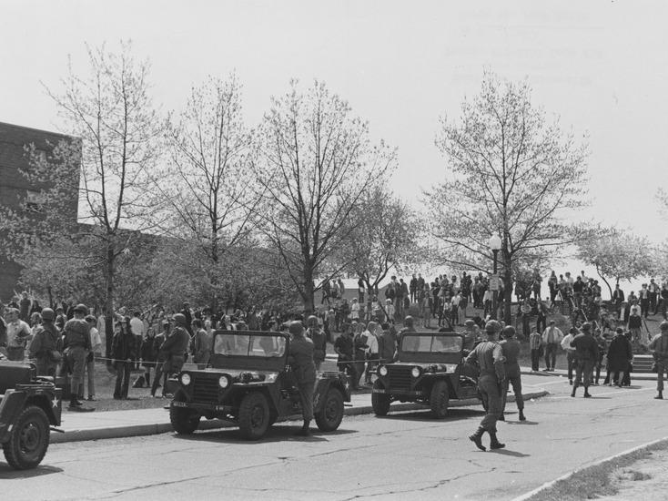 National Guard personnel and jeeps at Kent State University, with a crowd in the background.