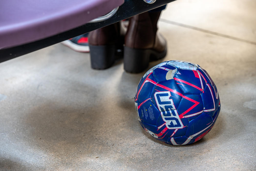 A partially deflated football lies under some chair at a Casa Alitas facility in Tucson, Arizona on Tuesday, March 26, 2024.