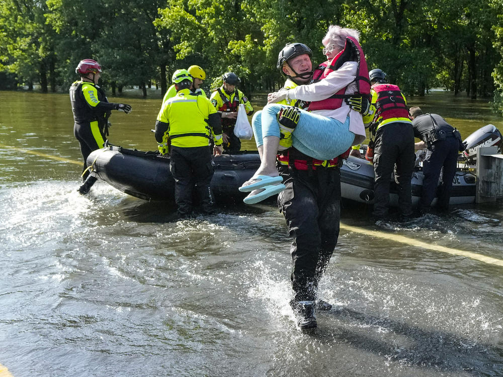 Conroe firefighter Cody Leroy carries a resident evacuated in a boat by the CFD Rapid Intervention Team from her flooded home in the aftermath of a severe storm on Thursday in Conroe, Texas.