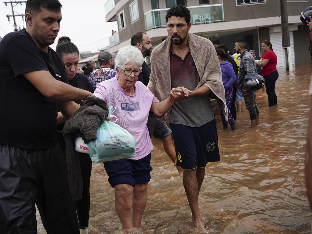 Residents evacuate from a neighborhood flooded by heavy rains, in Canoas, Rio Grande do Sul state, Brazil, Saturday, May 4, 2024.