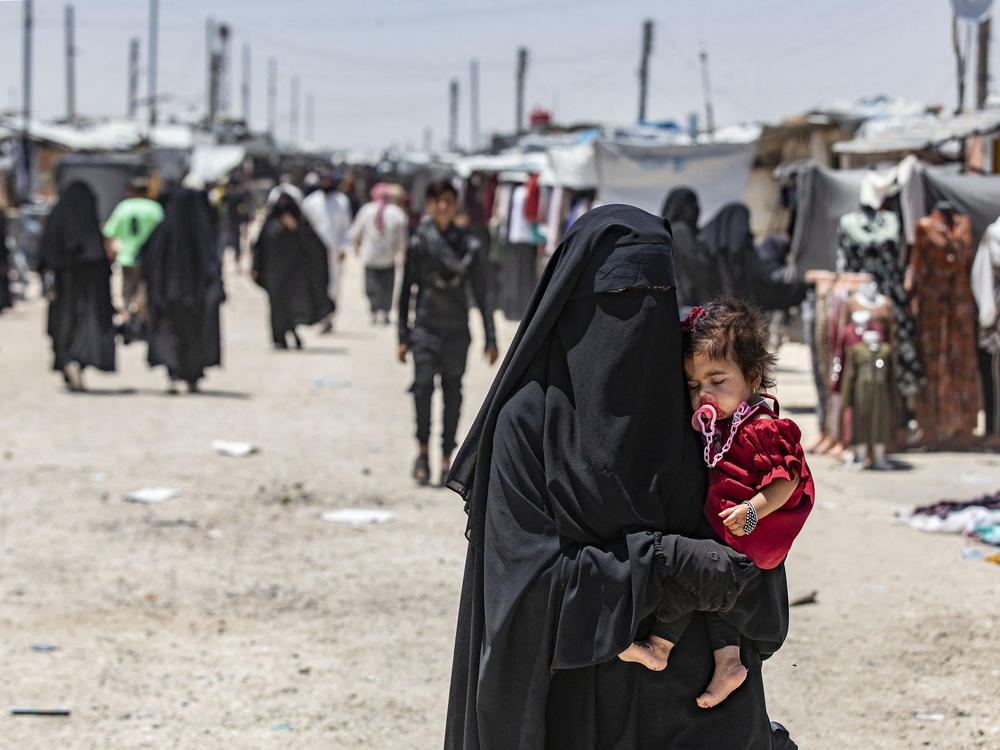 A woman carries a child as she walks through the al-Hol refugee camp in northeastern Syria in October 2023.
