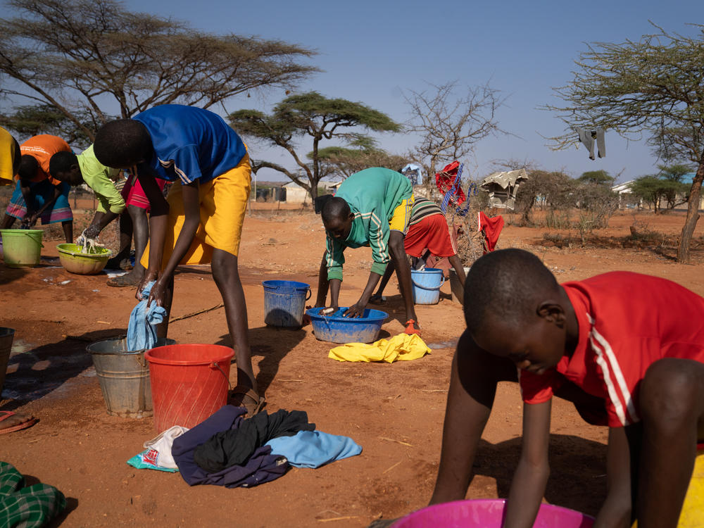 Loshaki (center) washes his clothes in a basin borrowed from one of the other students. Like Paris, he could not afford to buy his own.
