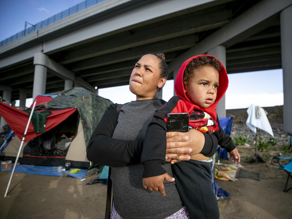 Rosbely Sira Linarez holds her infant son on April 24 in the north Denver encampment where they've been living with other South and Central American immigrants who arrived in Colorado in the last year.