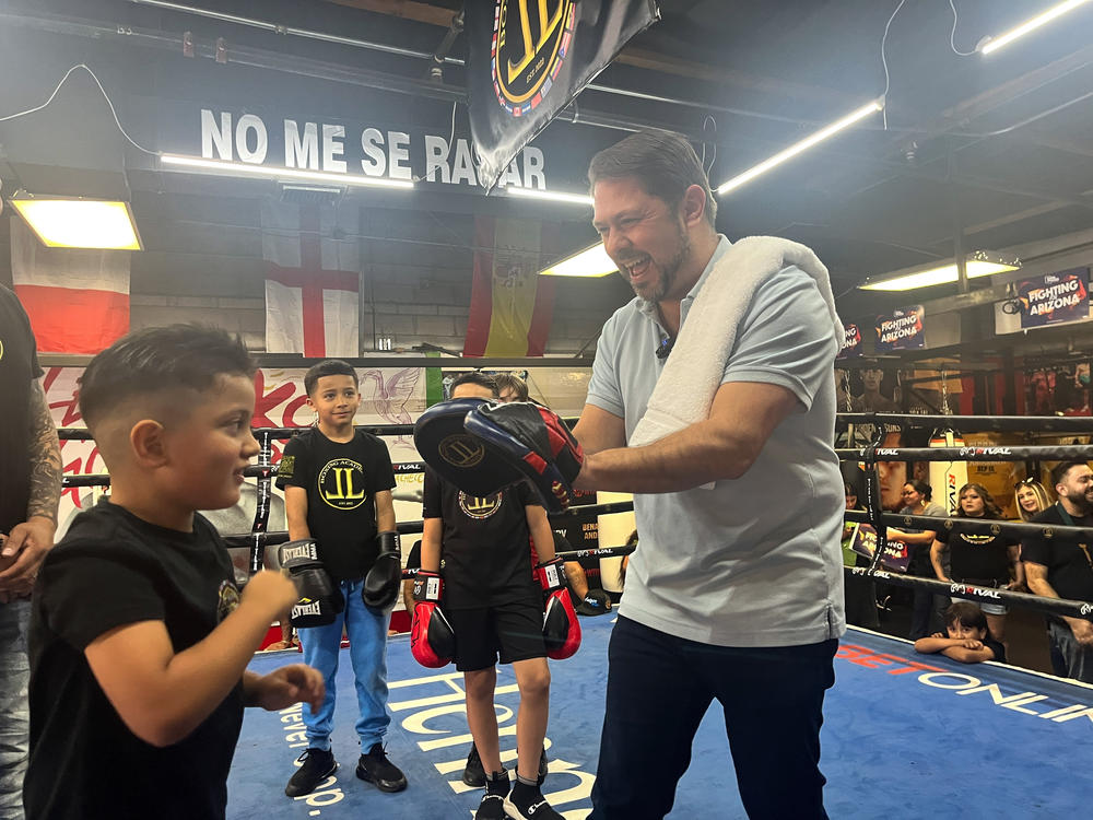 U.S. Rep. Ruben Gallego, a Democrat running for U.S. Senate, helps run a young boxer through pad training drills at the JL Boxing Academy on May 4.