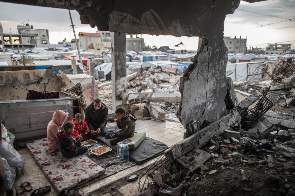 Palestinian Muhammad al-Durra, who lost his wife and whose house was destroyed in an Israeli attack, breaks his fast with his children during Ramadan in the wrecked house, in Rafah, March 20.