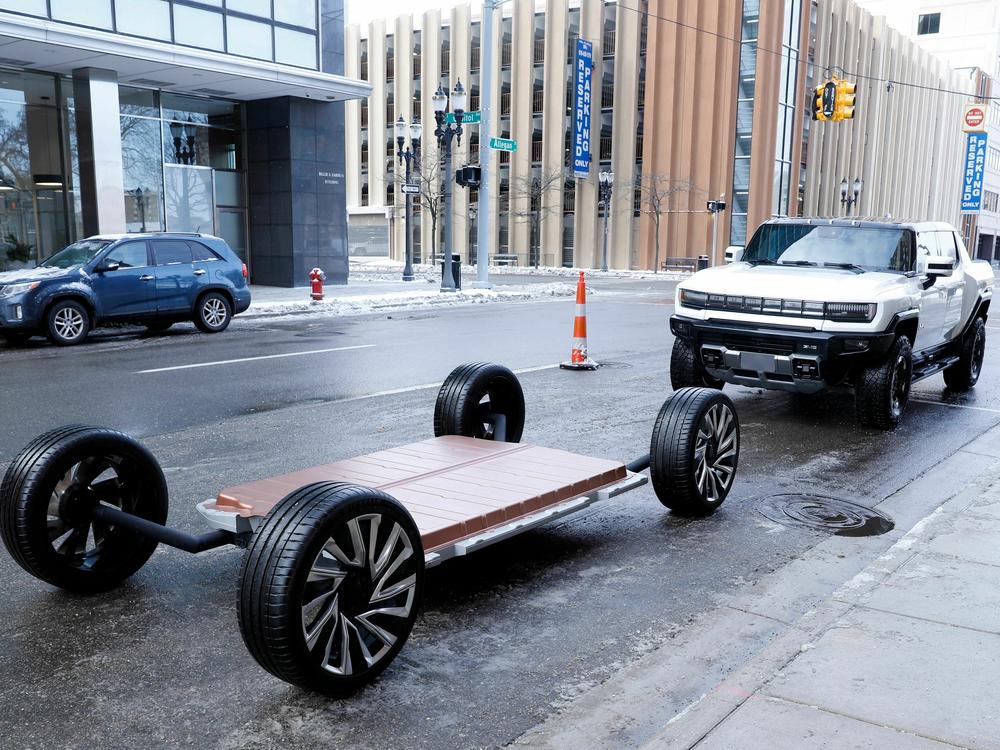 A battery pack and a GMC Hummer EV stand outside an event in Lansing, Mich., in 2022. Thea Riofrancos says car shoppers concerned about the environmental impacts of mining for batteries can choose a smaller EV, instead of a behemoth like a Hummer, to minimize the harms.