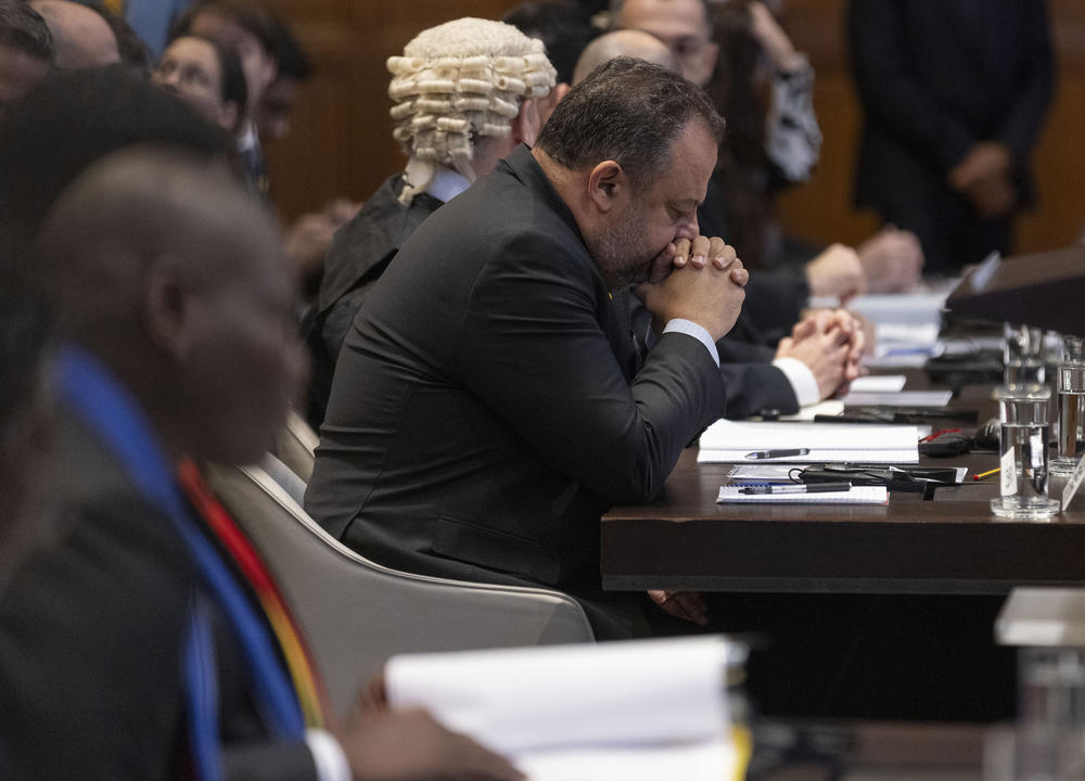 Israeli legal counselor Tal Becker looks down and South African Justice Minister Ronald Lamola sits in the foreground on Jan. 11 in The Hague, Netherlands, as South Africa requested the International Criminal Court to indicate measures concerning alleged violations of human rights by Israel in the Gaza Strip.