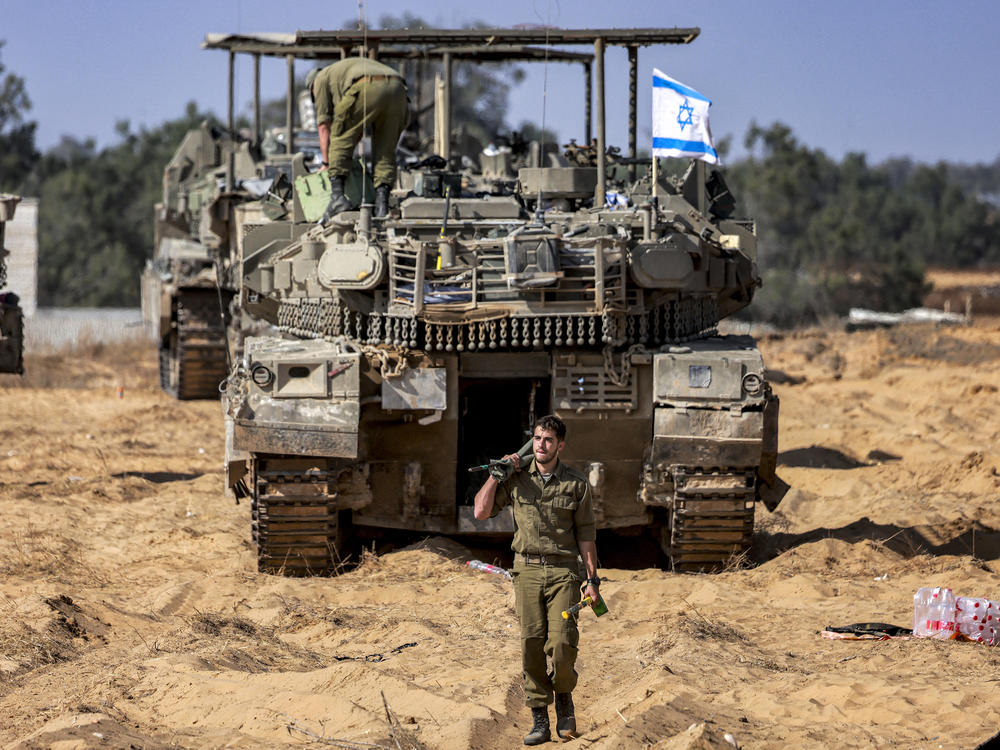 An Israeli army soldier walks past a main battle tank stationed at a position near the border with the Gaza Strip in southern Israel on April 30.