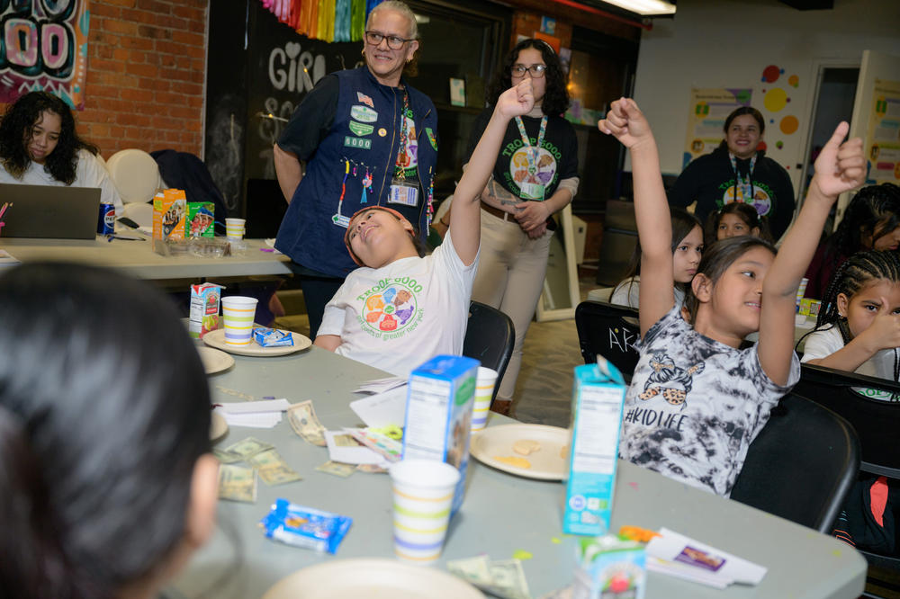 The girls excitedly raise their hands during an activity at Girl Scout Troop 6000's weekly meeting at the Row Hotel on Wednesday evening.