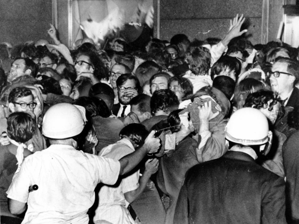 A police officer squirts tear gas at a crowd of anti-war demonstrators outside the Conrad Hilton Hotel in Chicago on Aug. 29, 1968.