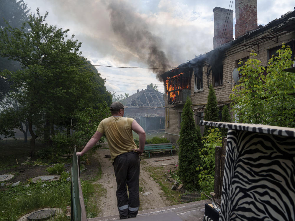 A local resident looks at a neighbour's house on fire after a Russian airstrike in Vovchansk, Ukraine, on Saturday, May 11, 2024.