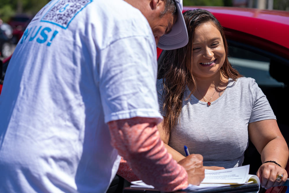 Wilmarie Rivera registers to vote with Humberto Orjuela of Poder Latinx outside the Presidente Supermarket.