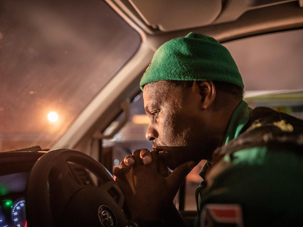 Paramedic Papinki Lebelo waits for a police escort before responding to an emergency call-out a Cape Town neighborhood. Due to a rise in attacks on paramedics, ambulance crews in large parts of the city will only go out when they have a police escort.