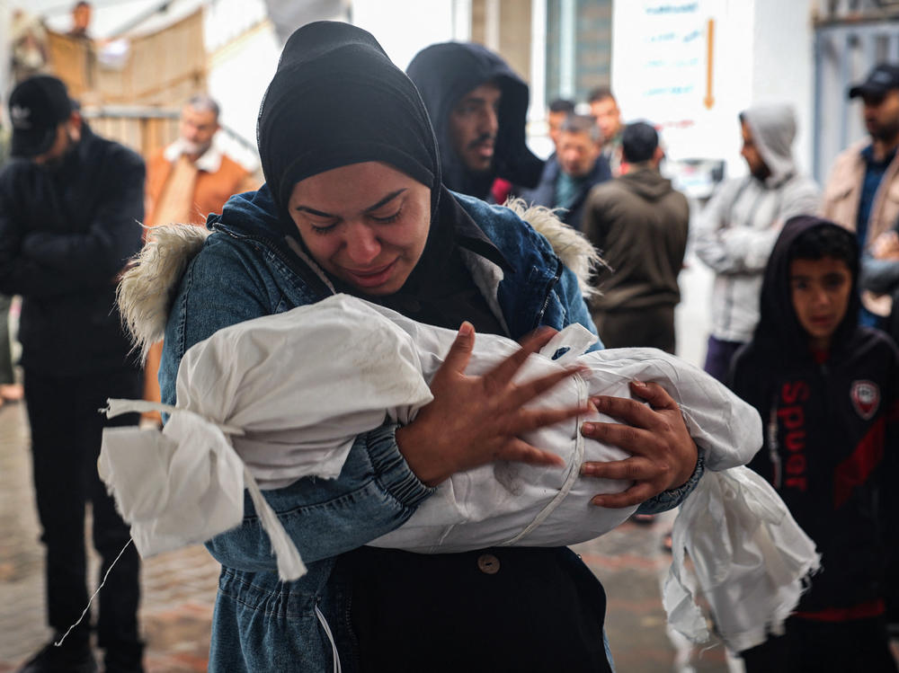 A woman mourns as she carries the shrouded body of a child killed following overnight Israeli strikes on Rafah in the southern Gaza Strip, on May 6.