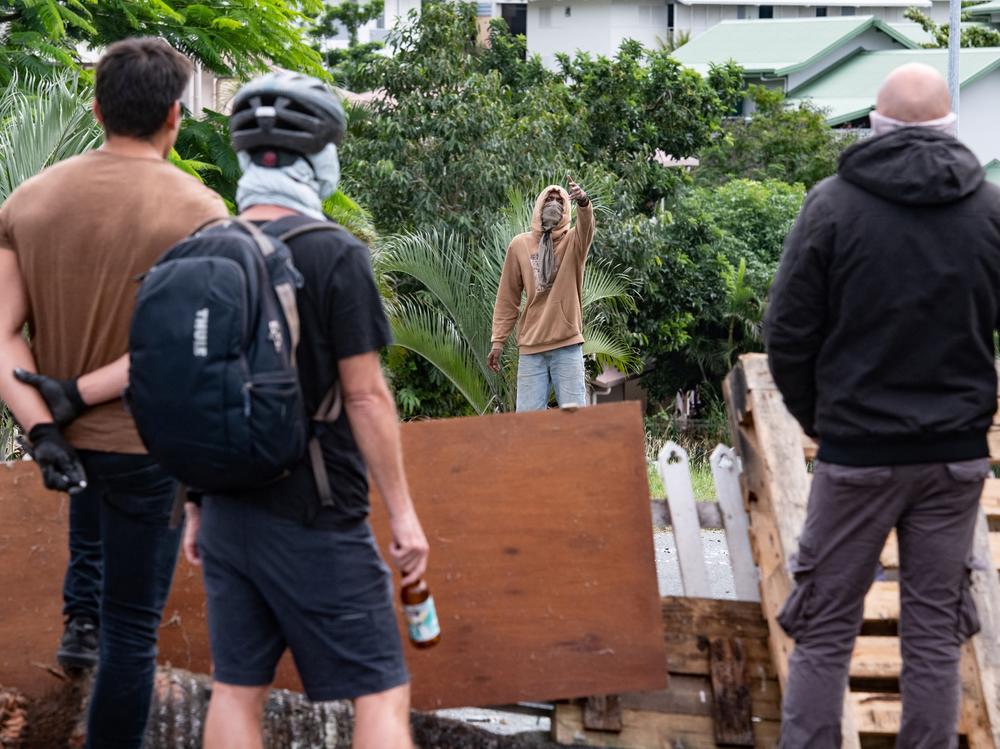 Masked residents watch an activist in Nouméa on Wednesday.