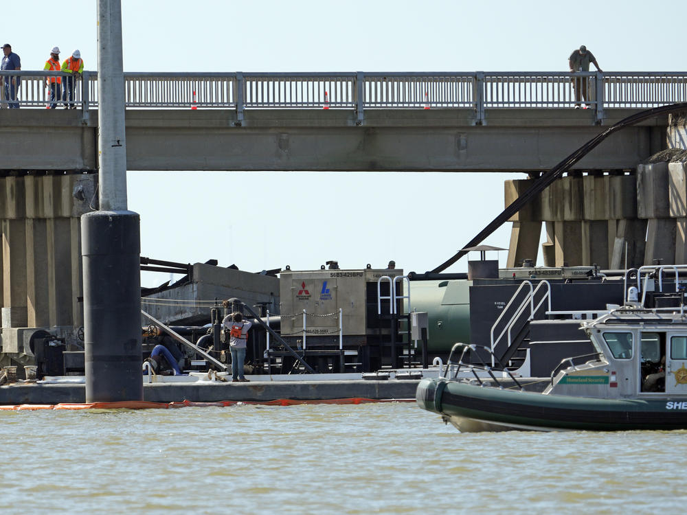 Workers survey the site where a barge crashed into the Pelican Island Bridge, on Wednesday in Galveston, Texas.