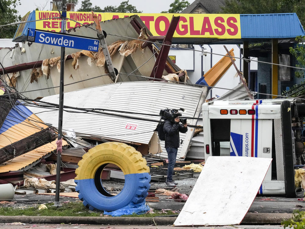 A video photojournalist shoots footage of damage at a tire shop at the intersection of Sowden and Bingle in the aftermath of a severe storm on Friday, in Houston.