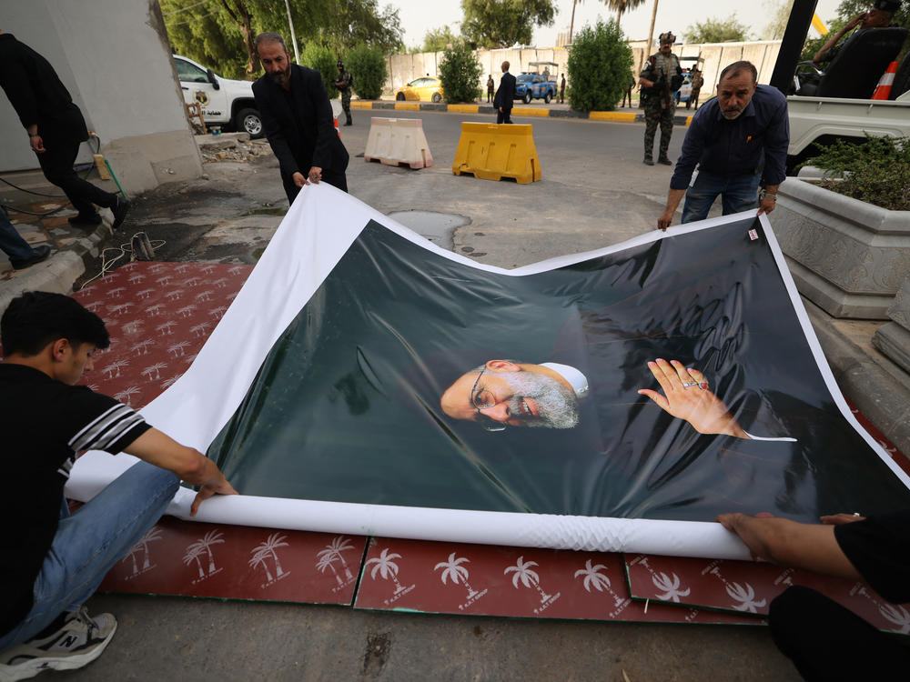 Men prepare to hang a huge portrait of Ebrahim Raisi outside the Islamic republic's embassy in Baghdad during a condolences service on Monday.