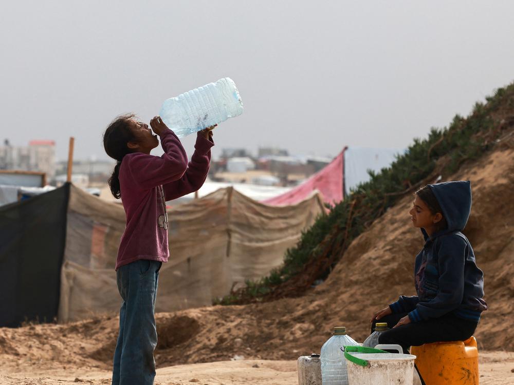 Displaced Palestinian children wait for a water supply tank to fill their containers amid soaring temperatures at a tent camp in Rafah in the southern Gaza Strip on April 26.